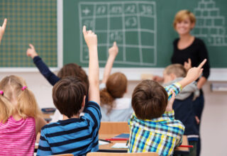 les élèves d'une classe lèvent tous la main pour participer