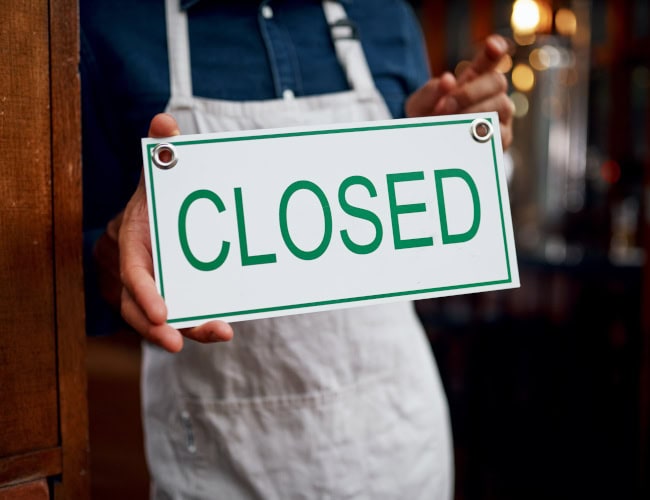 Closed sign, coffee shop and hands of person at entrance of small business for bankruptcy or recession. Closing, economy and financial crisis with employee at door cafe or restaurant for service - by StarDweller/peopleimages.com