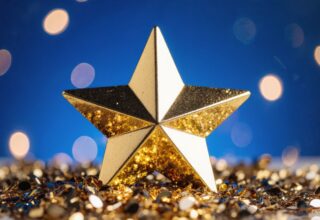 A golden star resting among shiny metallic confetti, symbol of success, victory, and triumph. By Giuseppe Cammino - AdobeStock. AI-generated