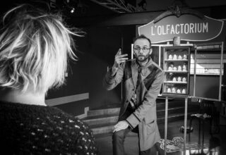 À l’accueil du public, un premier intervenant explique les connaissances acquises sur le monde des odeurs. Derrière lui, différents moulages de nez sont posés sur les étagères d’un olfactorium. © Philippe Lamotte