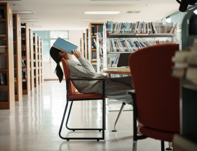 Asian student woman read books in library at university. Young girl stress tired have problem while study hard. Sadness concept. By Thanumporn - AdobeStock